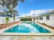 Inviting backyard pool with brick accents, surrounded by lush landscaping and clear blue skies at 405 S Lake Dr, Clearwater, FL 33755