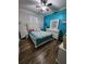 Bright bedroom featuring wood floors, a white bed with floral bedding, and a white dresser with a mirror at 4210 Pacente Loop, Zephyrhills, FL 33543