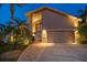 Well-lit home exterior with a two-car garage, a brick-paved walkway, and beautiful landscaping at twilight at 447 22Nd St, Belleair Beach, FL 33786