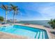 Inviting pool overlooking the water, surrounded by palm trees and blue skies at 447 22Nd St, Belleair Beach, FL 33786