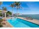 Exterior pool area featuring a clean pool, hot tub, lounge chairs, and tropical palms overlooking bay at 447 22Nd St, Belleair Beach, FL 33786