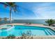 Inviting pool overlooking the water, surrounded by palm trees and blue skies at 447 22Nd St, Belleair Beach, FL 33786