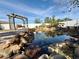 Picturesque backyard pond featuring rock accents, water plants, and a charming wooden swing pergola at 6753 Thorman Rd, Port Charlotte, FL 33981