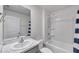 A well-lit bathroom with a tub and shower, a modern vanity with a marble countertop, and stylish fixtures at 7608 Broad Pointe Dr, Zephyrhills, FL 33540