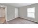 A neutral-toned bedroom featuring plush carpeting, a window, and a view into an adjoining tiled room at 7608 Broad Pointe Dr, Zephyrhills, FL 33540