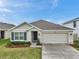 Attractive single-story home with a two-car garage, gray shutters, tidy landscaping, and a well-maintained lawn at 7608 Broad Pointe Dr, Zephyrhills, FL 33540