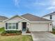 Charming single Gathering home with well-manicured lawn and front garden featuring gray shutters and a two car garage at 7608 Broad Pointe Dr, Zephyrhills, FL 33540