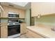 Kitchen with light wood cabinets, gas range, stainless steel microwave, and beige countertops at 800 71St N Ave # 8, St Petersburg, FL 33702