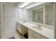 Bathroom with a long vanity with double sinks, a large mirror and cabinets, adjacent to a shower behind glass doors at 860 Glen More Ct # B, Palm Harbor, FL 34684