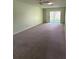 Spacious carpeted living room with neutral walls, ceiling fan, and sliding glass doors to outdoor area at 860 Glen More Ct # B, Palm Harbor, FL 34684