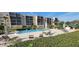 Community pool with lounge seating and greenery in front of a multi-story condominium building at 90 S Highland Ave # 224, Tarpon Springs, FL 34689
