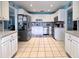 Open kitchen layout with stainless steel appliances, white cabinets, blue backsplash, and tile flooring, ideal for cooking at 903 Setter Ct, Seffner, FL 33584