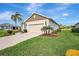 View of house that includes a two-car garage, palm trees, and vibrant green lawn at 11750 Fennemore Way, Parrish, FL 34219