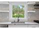 Close up of a farmhouse sink set in a countertop, complimented by tiled backsplash and white shelving at 124 Bosphorous Ave, Tampa, FL 33606