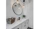 Bright bathroom featuring a round mirror, modern pendant lights, a white vanity, and dark hardware at 14247 Spanish Wells Dr, Hudson, FL 34667