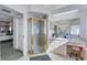 Bright bathroom featuring a glass enclosed shower, vanity with seating, and doorway into the carpeted bedroom at 14247 Spanish Wells Dr, Hudson, FL 34667