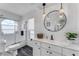 Bright bathroom with a round mirror, pendant lighting, a glass shower door, and updated cabinets at 14247 Spanish Wells Dr, Hudson, FL 34667