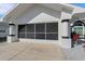 Attached garage featuring a screened garage door, decorative columns, and a manicured landscape at 14247 Spanish Wells Dr, Hudson, FL 34667