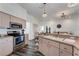 Modern kitchen with stainless steel appliances, light wood cabinets, stylish pendant lighting, and an open layout at 14247 Spanish Wells Dr, Hudson, FL 34667