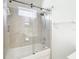 Bathroom showcasing a shower over tub with glass doors, bright tile surround, and a window at 18111 Diamond Cove Ct, Tampa, FL 33647
