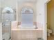 Bright bathroom with shower, soaking tub, and arched window with privacy blinds at 18111 Diamond Cove Ct, Tampa, FL 33647
