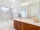 Bathroom featuring wooden cabinets, a large mirror, shower over tub and neutral color palette at 18111 Diamond Cove Ct, Tampa, FL 33647