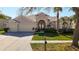 Beautiful home featuring a well-manicured lawn, arched entryway, and an attached two car garage at 18111 Diamond Cove Ct, Tampa, FL 33647