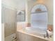 Bright bathroom featuring a soaking tub, glass shower, and arched window at 18111 Diamond Cove Ct, Tampa, FL 33647