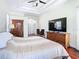 Spacious main bedroom with tray ceiling, warm wood floors, and large entertainment center at 18111 Diamond Cove Ct, Tampa, FL 33647