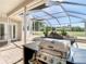 Outdoor kitchen overlooking private screened pool with waterfall feature and lush landscaping at 18111 Diamond Cove Ct, Tampa, FL 33647