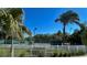 A view of the community tennis court through a white fence with palm trees in the background at 18111 Diamond Cove Ct, Tampa, FL 33647