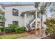 Two-story condo with white exterior, wooden stairs, and charming curb appeal from flower pots and green bushes at 1822 Lake Cypress Dr # 1822, Safety Harbor, FL 34695