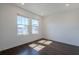 Sunlit bedroom featuring hardwood floors, white walls, and a pair of windows with neighborhood views at 3025 Bermuda Sloop Cir, Ruskin, FL 33570