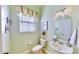 Charming powder room with a pedestal sink, decorative mirror, soft green walls, and natural light at 310 Manns Harbor Dr, Apollo Beach, FL 33572