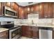 Well-lit kitchen featuring granite countertops, stainless steel appliances, and dark brown cabinetry at 3303 W Price Ave, Tampa, FL 33611