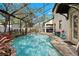 A screened-in pool area with a sparkling pool, brick patio, and lush landscaping at 3605 E Tampa Cir, Tampa, FL 33629