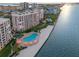 Aerial view of condo building, beach, and pool area with lounge chairs overlooking the water at 4951 Bacopa S Ln # 801, St Petersburg, FL 33715