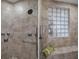 Close up of the walk-in shower with pebble flooring, a glass block window and a shower seat at 4951 Bacopa S Ln # 801, St Petersburg, FL 33715