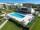 Aerial view of community pool and outdoor lounge area surrounded by lush landscaping and multiple residential buildings at 50 Coe Rd # 111, Belleair, FL 33756