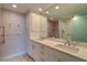 Bright bathroom featuring double sinks, white cabinets, and a large mirror reflecting the shower at 50 Coe Rd # 223, Belleair, FL 33756