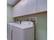 Bright laundry room with white washer and dryer and overhead cabinets at 50 Coe Rd # 223, Belleair, FL 33756