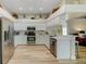 Bright kitchen features modern, stainless appliances, white cabinets, and light countertops and wood flooring at 503 Old Grove Dr, Lutz, FL 33548