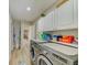 Well-lit laundry room featuring stainless steel washer and dryer, complemented by white cabinetry and wood-look flooring at 503 Old Grove Dr, Lutz, FL 33548