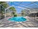 Beautiful screened-in pool area with a freeform pool and spa surrounded by lush landscaping, seating and dining at 503 Old Grove Dr, Lutz, FL 33548