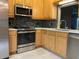 Bright kitchen features stainless steel appliances, wooden cabinets, tile backsplash, and solid surface countertops at 6815 Dali Ave # F101, Land O Lakes, FL 34637