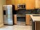 Bright kitchen features stainless steel appliances, wooden cabinets, tile backsplash, and solid surface countertops at 6815 Dali Ave # F101, Land O Lakes, FL 34637