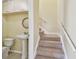 Hallway featuring a half bath with pedestal sink and access to the carpeted staircase at 7200 Ulmerton Rd # B4, Largo, FL 33771
