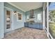 An outdoor kitchen on a brick patio features a stainless grill, range hood and sink with blue cabinets at 735 Manns Harbor Dr, Apollo Beach, FL 33572