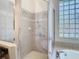 Walk-in shower and soaking tub featuring neutral tilework and decorative glass block at 7743 Bingham Ct, Tampa, FL 33625