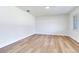 A clean and minimalist bedroom with light wood floors, white walls, and a bright window at 303 Suzette Dr, Brandon, FL 33511